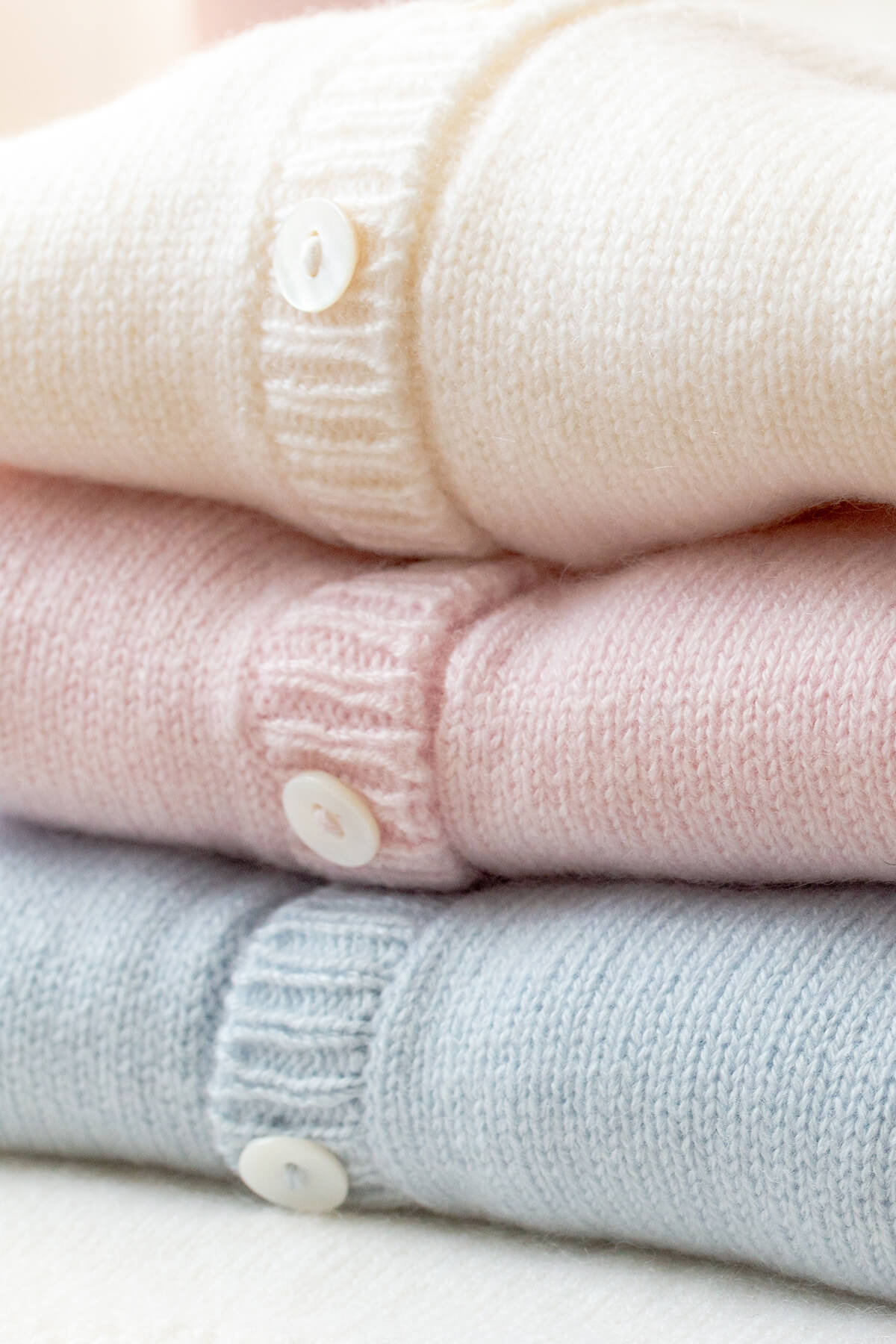 Johnstons of Elgin Hand Knitted Cashmere Baby Cardigan in Ecru, Blush & Powder Blue on a white background