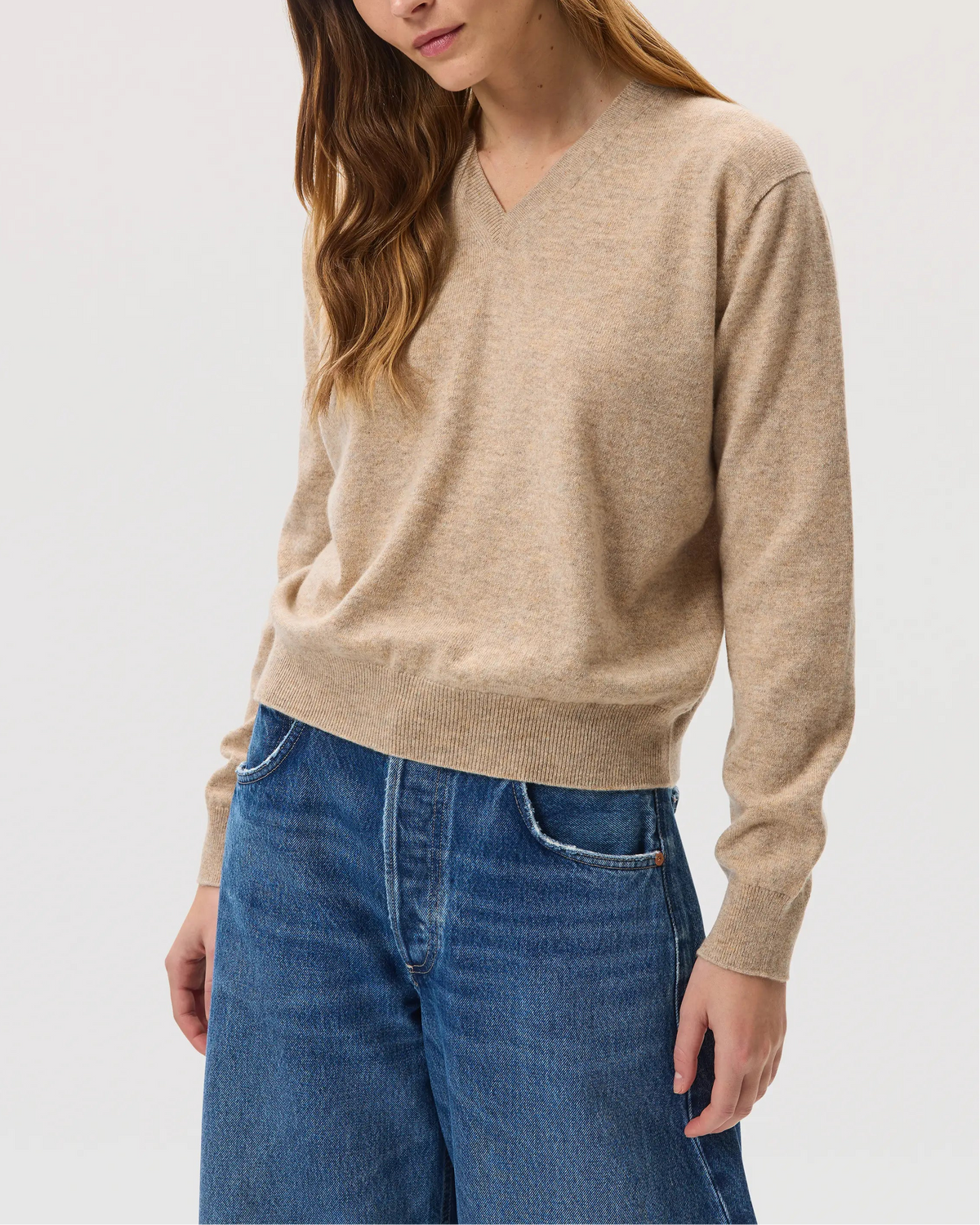 Model wearing Johnstons of Elgin SS25 Women's Knitwear Oatmeal Classic Cashmere V Neck with blue jeans KAI05143HB0210