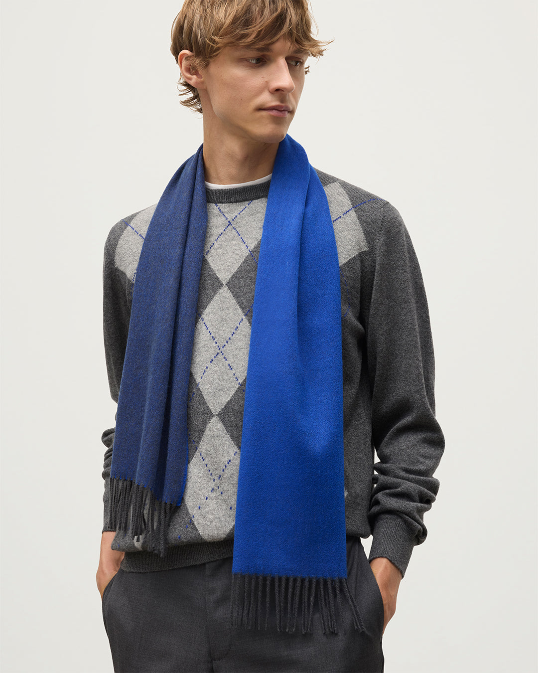MALE MODEL WEARS JOHNSTONS OF ELGIN BLUE BARD SCARF 100% CASHMERE OVER A GREY ARGYLL SWEATER WA002560RU7727ONE