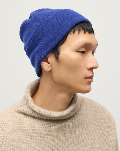 JOHNSTONS OF ELGIN BRAEMAR BEANIE BLUE 100% CASHMERE ON A MALE MODEL WITH NATURAL KESTER CASHMERE FUNNEL NECK SWEATER HAE02655SD5326ONE