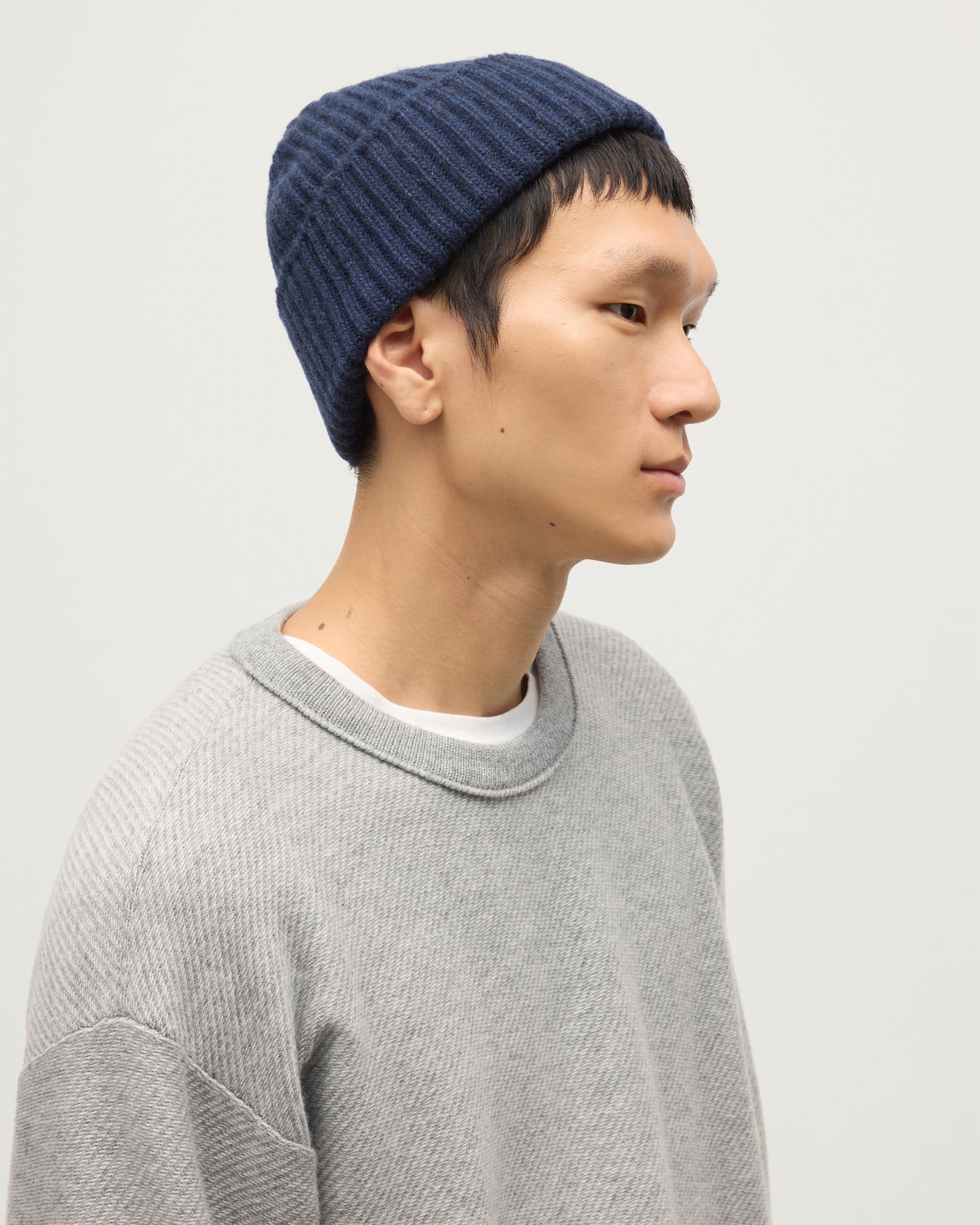 JOHNSTONS OF ELGIN LOVAT HAT NAVY 100% CASHMERE ON A MALE MODEL WORN WITH A GREY CASHMERE SWEATER HAY03614HD7350ONE