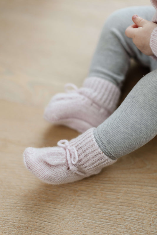 Johnstons of Elgin Hand Knitted Cashmere Baby Booties in Blush on pink check background JA000114SE0208ONE