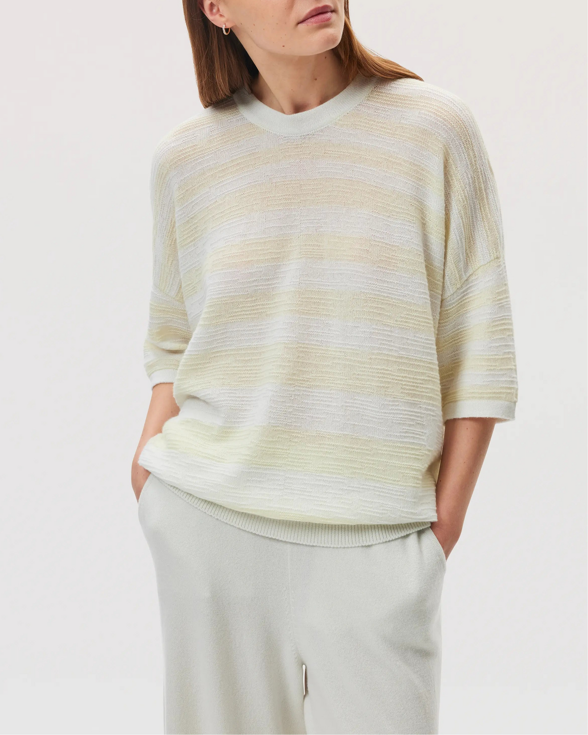 Female model wearing Johnstons of Elgin SS25 Unisex Knitwear White & Lemon Textured Stripe Oversized Cashmere T-Shirt against a white backdrop  KAA05414Q25127