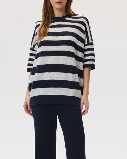 Female model wearing Johnstons of Elgin SS25 Unisex Knitwear Navy & White Textured Stripe Oversized Cashmere T-Shirt with navy trousers against a white backdrop KAA05414Q25123