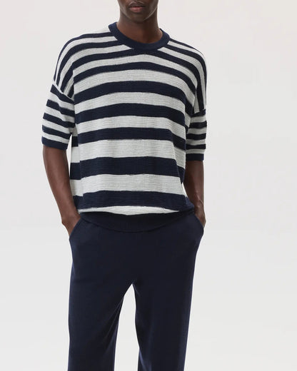 Male model wearing Johnstons of Elgin SS25 Unisex Knitwear Navy & White Textured Stripe Oversized Cashmere T-Shirt with navy cashmere joggers KAA05414Q25123
