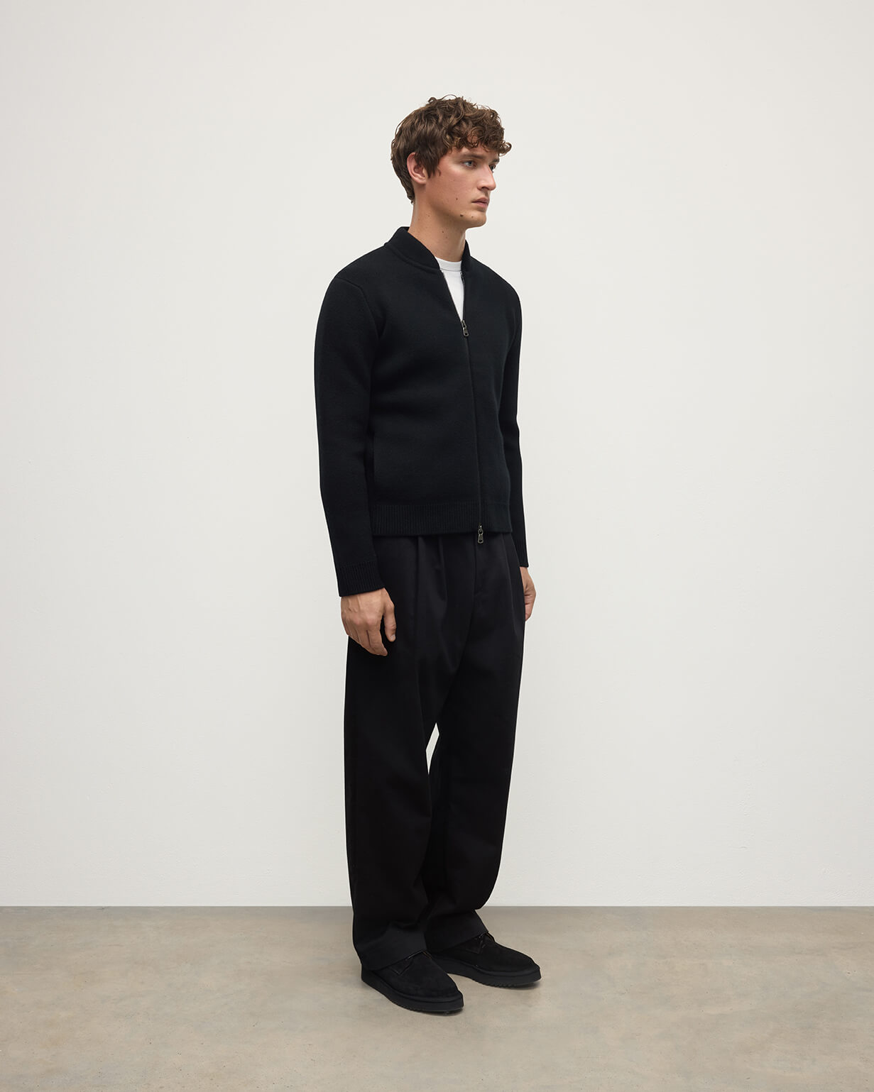 Johnstons of Elgin AW25 Men's Knitwear Black Cashmere Milano Stitch Zip Jacket with black trousers and a white t-shirt  KAA05443SA0900