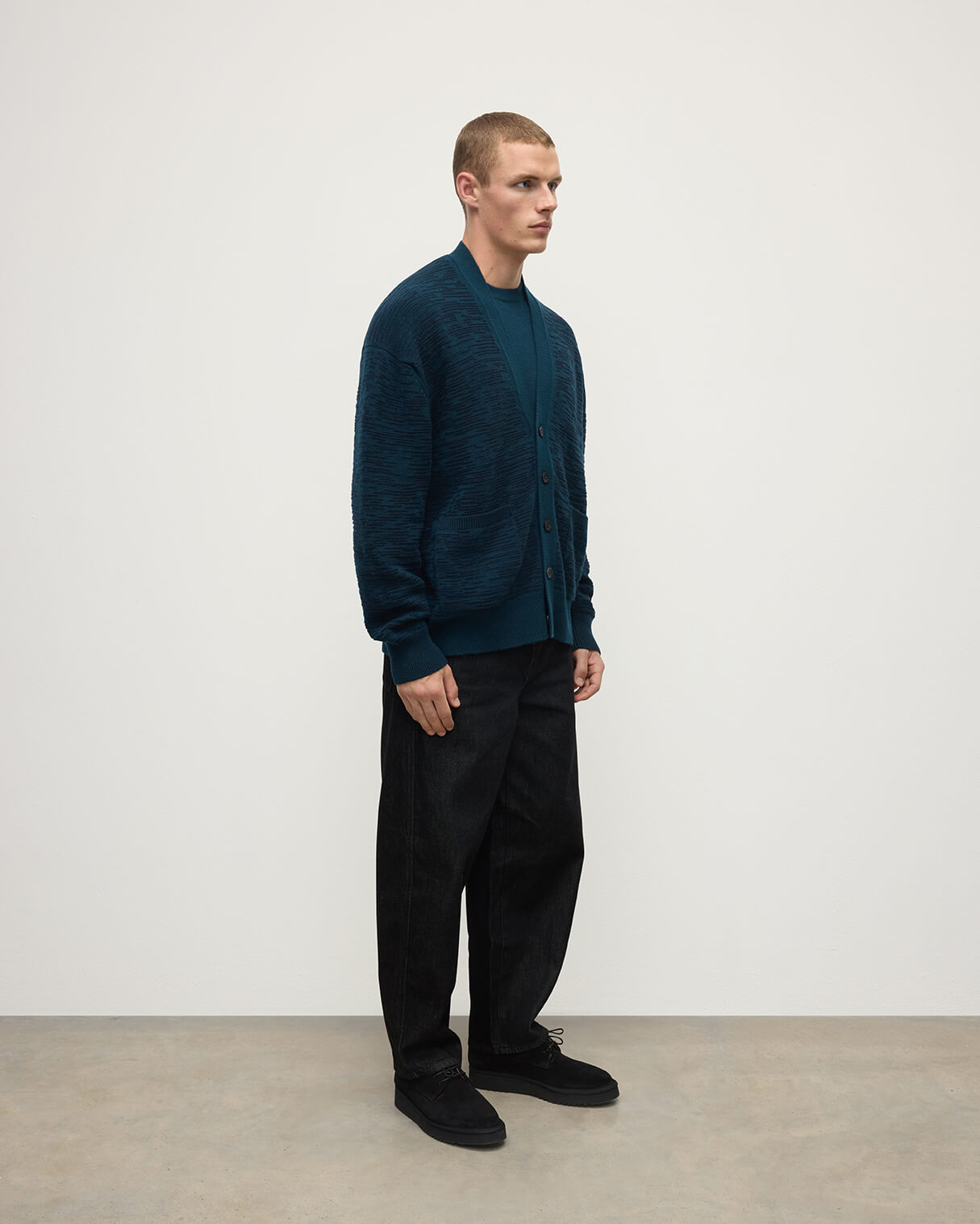 Side View of model wearing Johnstons of Elgin AW25 Men's Knitwear Bottle Green & Dark Navy Plaited Texture Green Cashmere Cardigan KAA05579Q25389