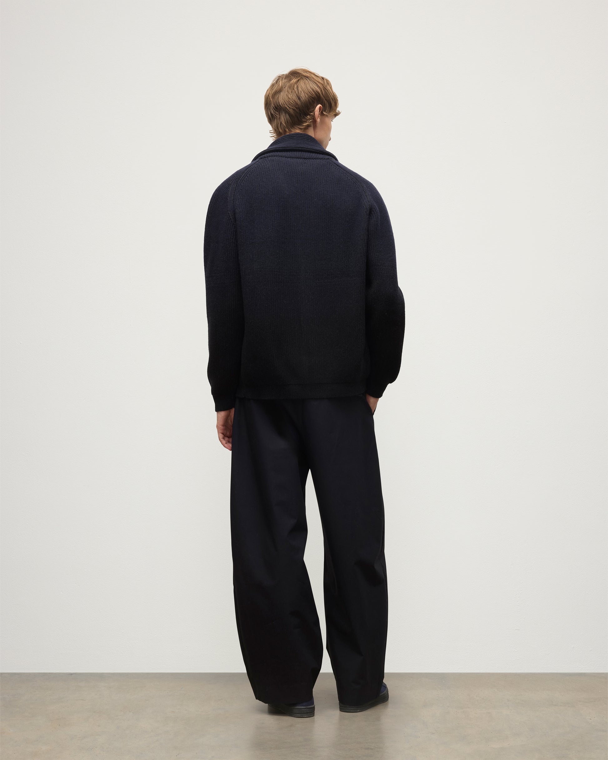 MALE MODEL WEARING JOHNSTONS OF ELGIN PIONEER SHAWL CARDIGAN NAVY & BLACK 100% CASHMERE WITH BLACK SUPERFINE CASHMERE SWEATER AND NAVY TROUSERS KAA05750Q25947