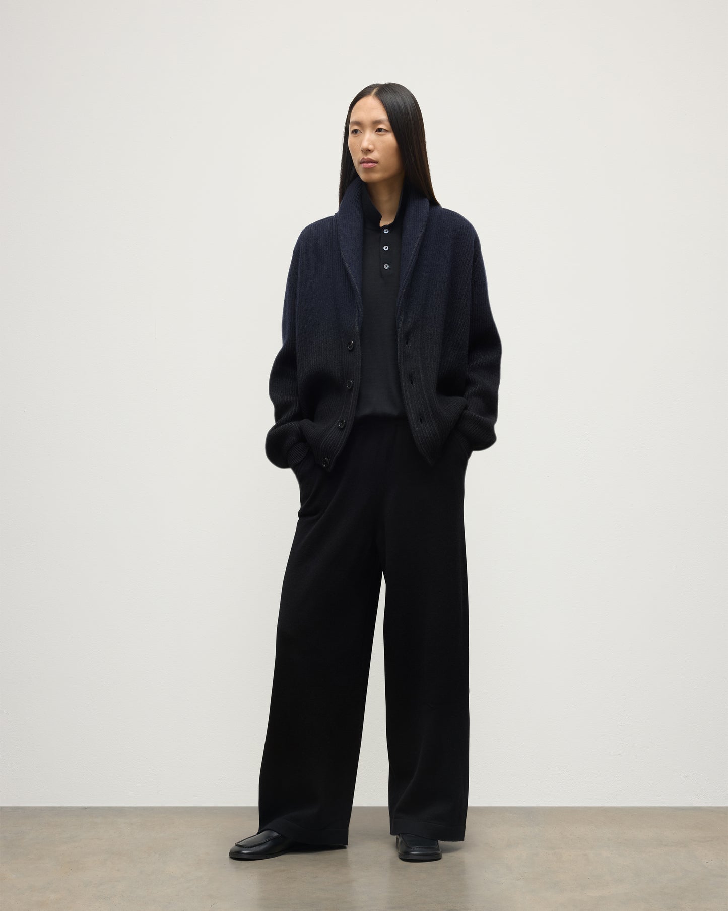 FEMALE MODEL WEARING JOHNSTONS OF ELGIN PIONEER SHAWL CARDIGAN NAVY & BLACK 100% CASHMERE WITH BLACK TROUSERS AND POLO SHIRT UAA05750Q25947