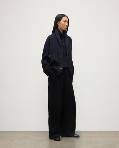 FEMALE MODEL WEARING JOHNSTONS OF ELGIN PIONEER SHAWL CARDIGAN NAVY & BLACK 100% CASHMERE WITH BLACK TROUSERS, SHOES AND POLO SHIRT UAA05750Q25947
