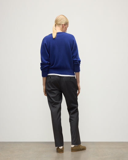 BACK OF MODEL WEARING JOHNSTONS OF ELGIN WOMENS STELLA SWEATSHIRT BLUE 100% CASHMERE OVER A WHITE T_SHIRT, WITH DARK GREY TROUSERS KAA05770SD5326