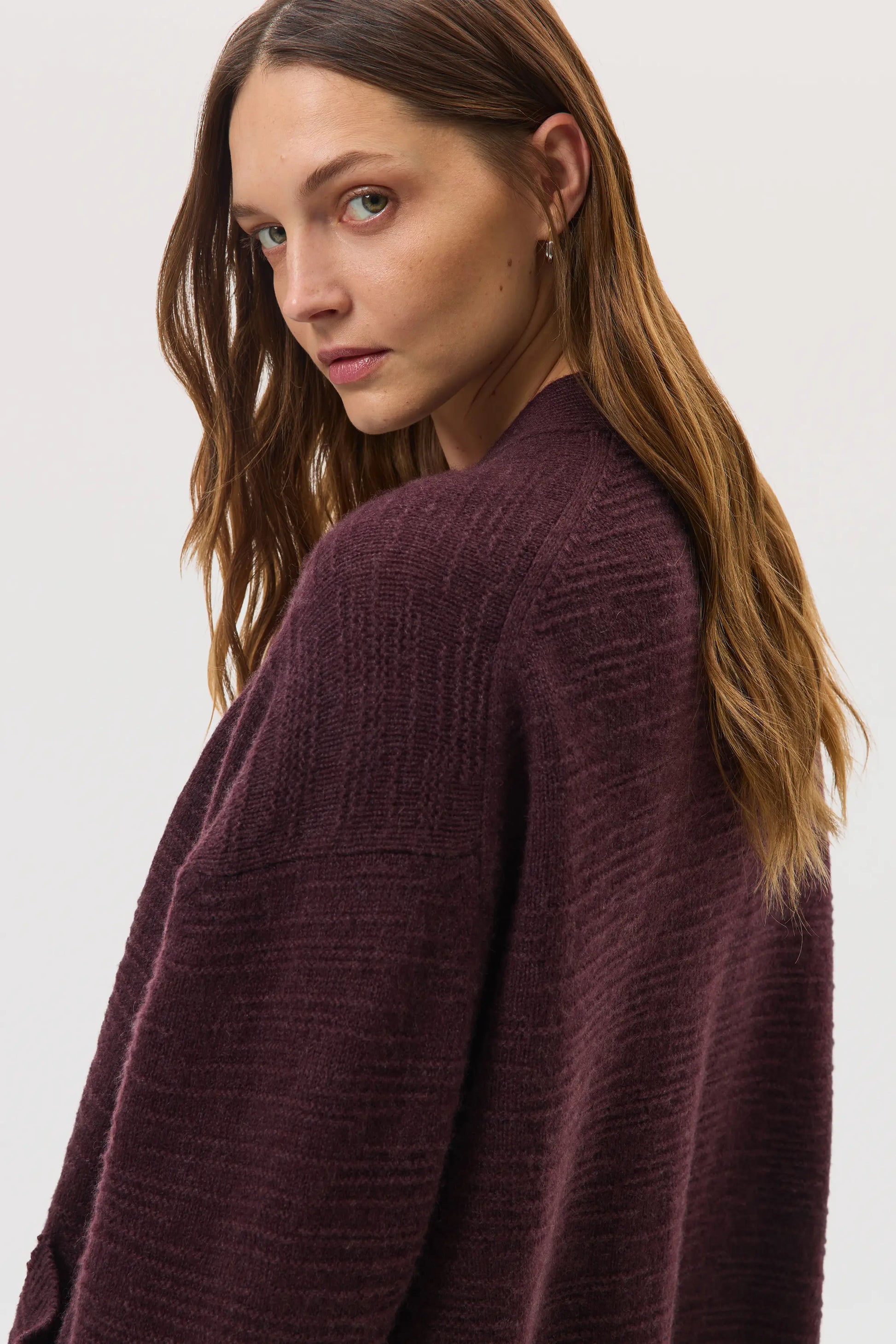 Female model wearing Johnstons of Elgin SS25 Unisex Knitwear Rosewood Textured Cashmere Cardigan against a white background KAC05415SB7089