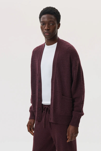 Male model wearing Johnstons of Elgin SS25 Unisex Knitwear Rosewood Textured Cashmere Cardigan with superfine cashmere sweater in white against a white background KAC05415SB7089