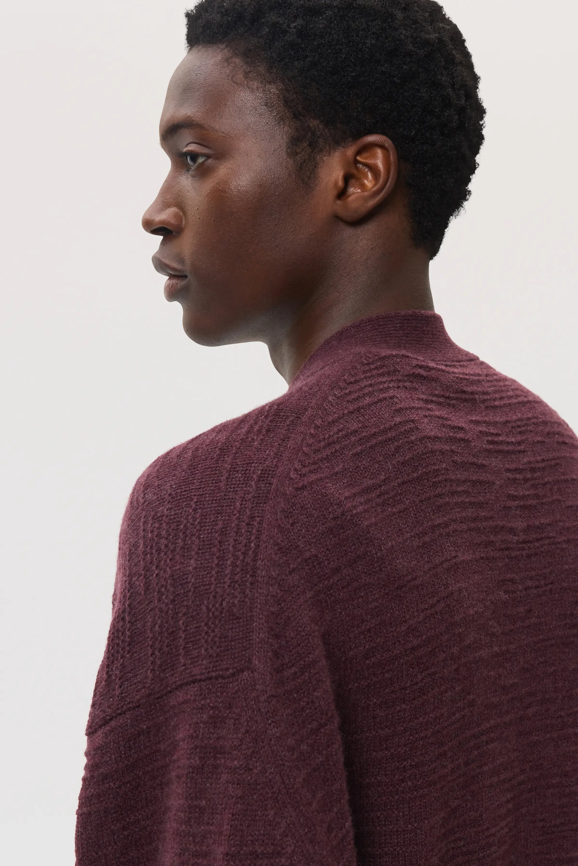 Male model wearing Johnstons of Elgin SS25 Unisex Knitwear Rosewood Textured Cashmere Cardigan on a white background KAC05415SB7089