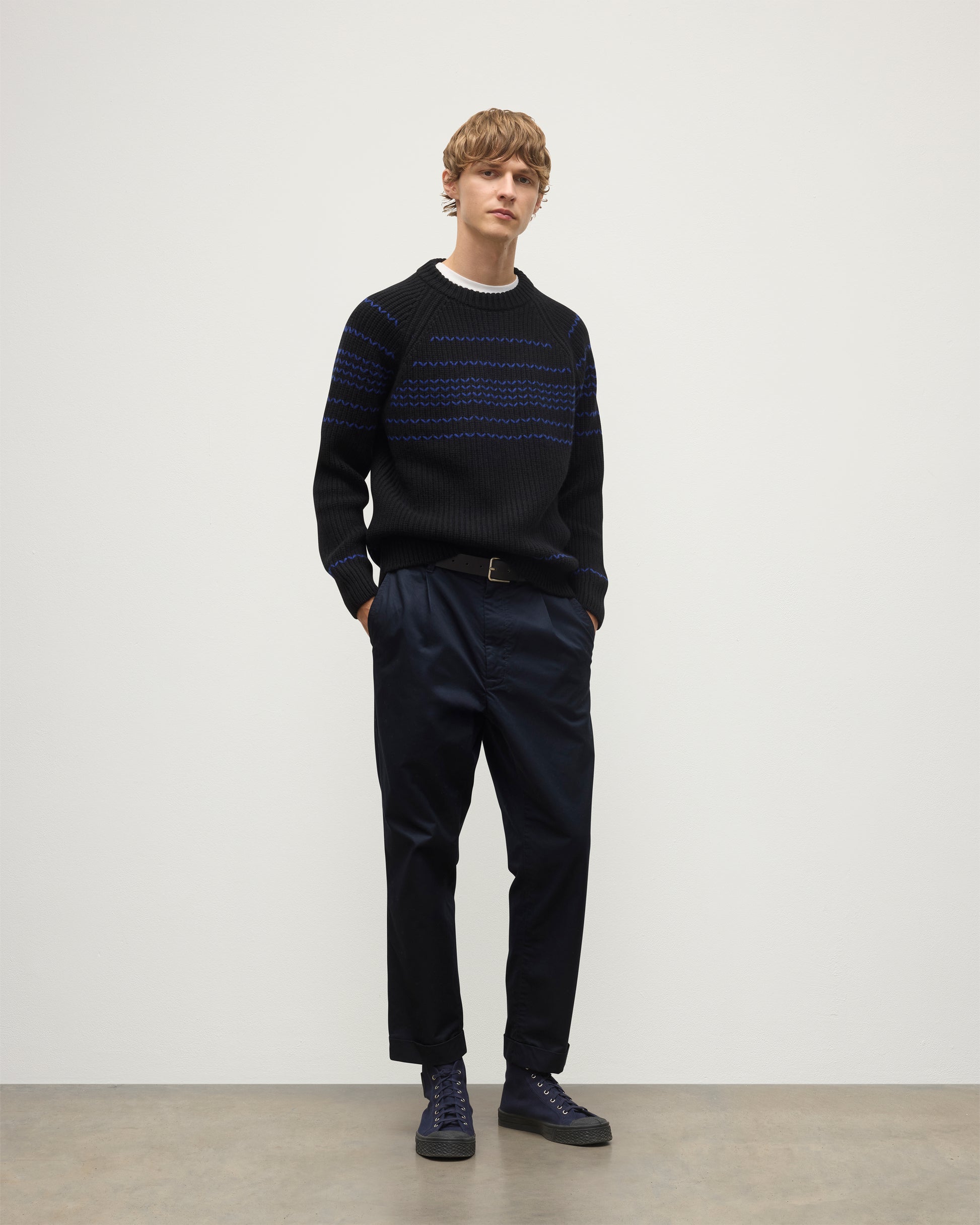 MODEL WEARS JOHNSTONS OF ELGIN  MENS SUMMIT CREW SWEATER BLACK & BLUE 100% CASHMERE OVER A WHITE T-SHIRT WITH NAVY TROUSERS KAC05752Q25949