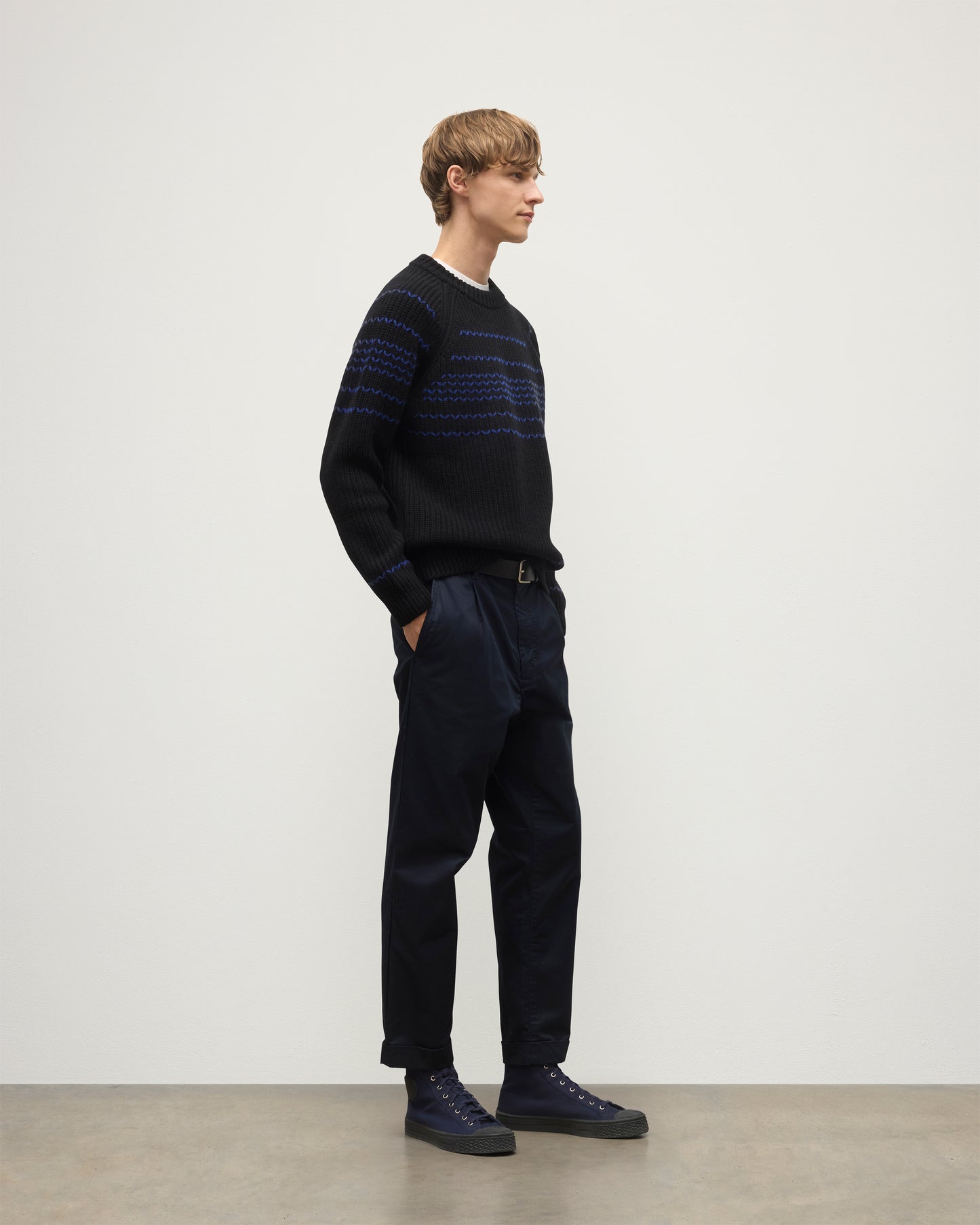 MODEL WEARS JOHNSTONS OF ELGIN  MENS SUMMIT CREW SWEATER BLACK & BLUE 100% CASHMERE OVER A WHITE T-SHIRT WITH NAVY TROUSERS KAC05752Q25949