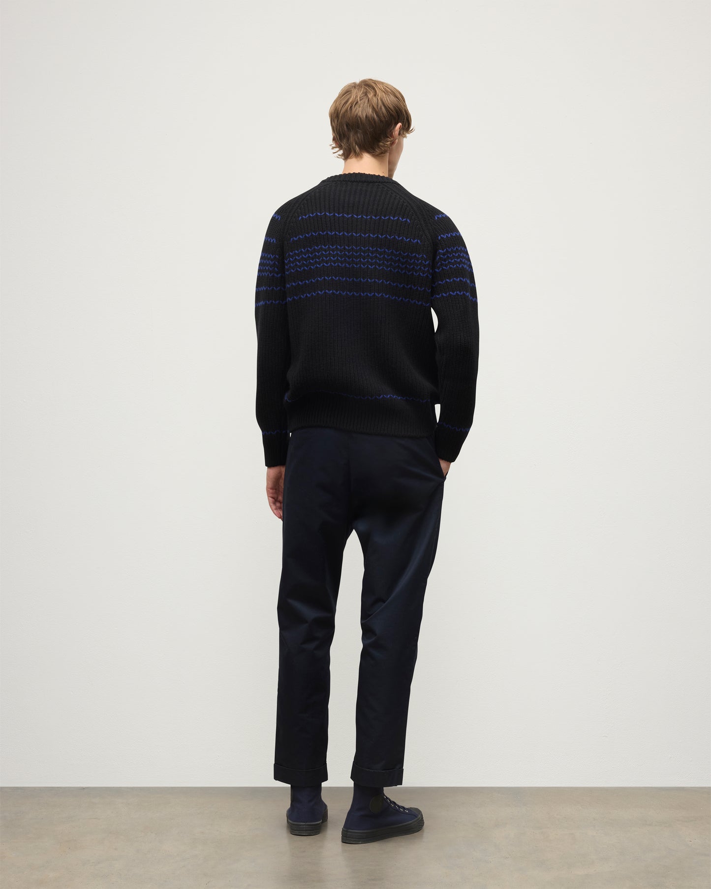 MODEL WEARS JOHNSTONS OF ELGIN  MENS SUMMIT CREW SWEATER BLACK & BLUE 100% CASHMERE OVER A WHITE T-SHIRT WITH NAVY TROUSERS KAC05752Q25949