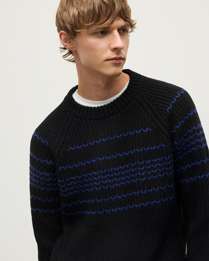 MODEL WEARS JOHNSTONS OF ELGIN  MENS SUMMIT CREW SWEATER BLACK & BLUE 100% CASHMERE OVER A WHITE T-SHIRT WITH NAVY TROUSERS KAC05752Q25949