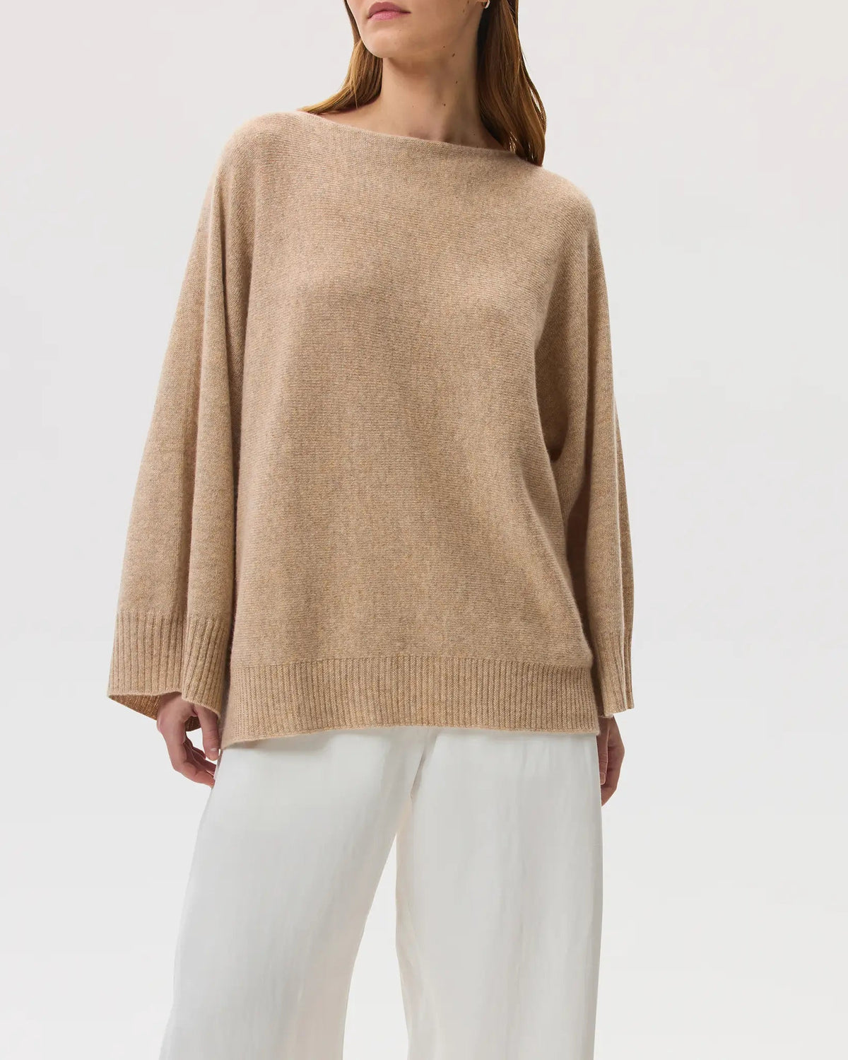 Model wearing Johnstons of Elgin SS25 Women's Knitwear Oatmeal Cashmere Cape Jumper with white trousers on a white background KAI05048HB0210