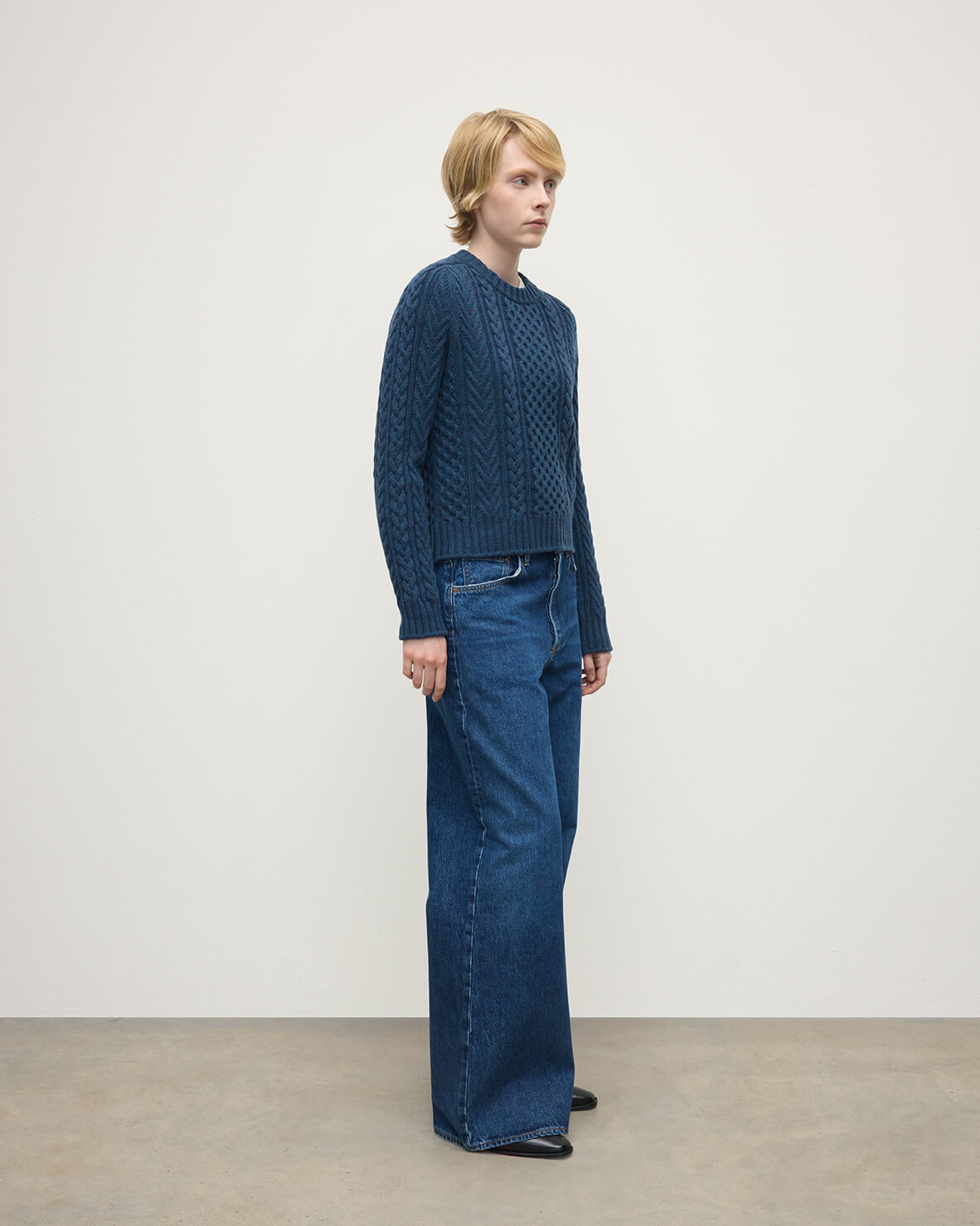 Model wears Johnstons of Elgin AW25 Women's Knitwear Heather Navy Aran Cable Navy Cashmere Jumper Side View KAI05086HD7321