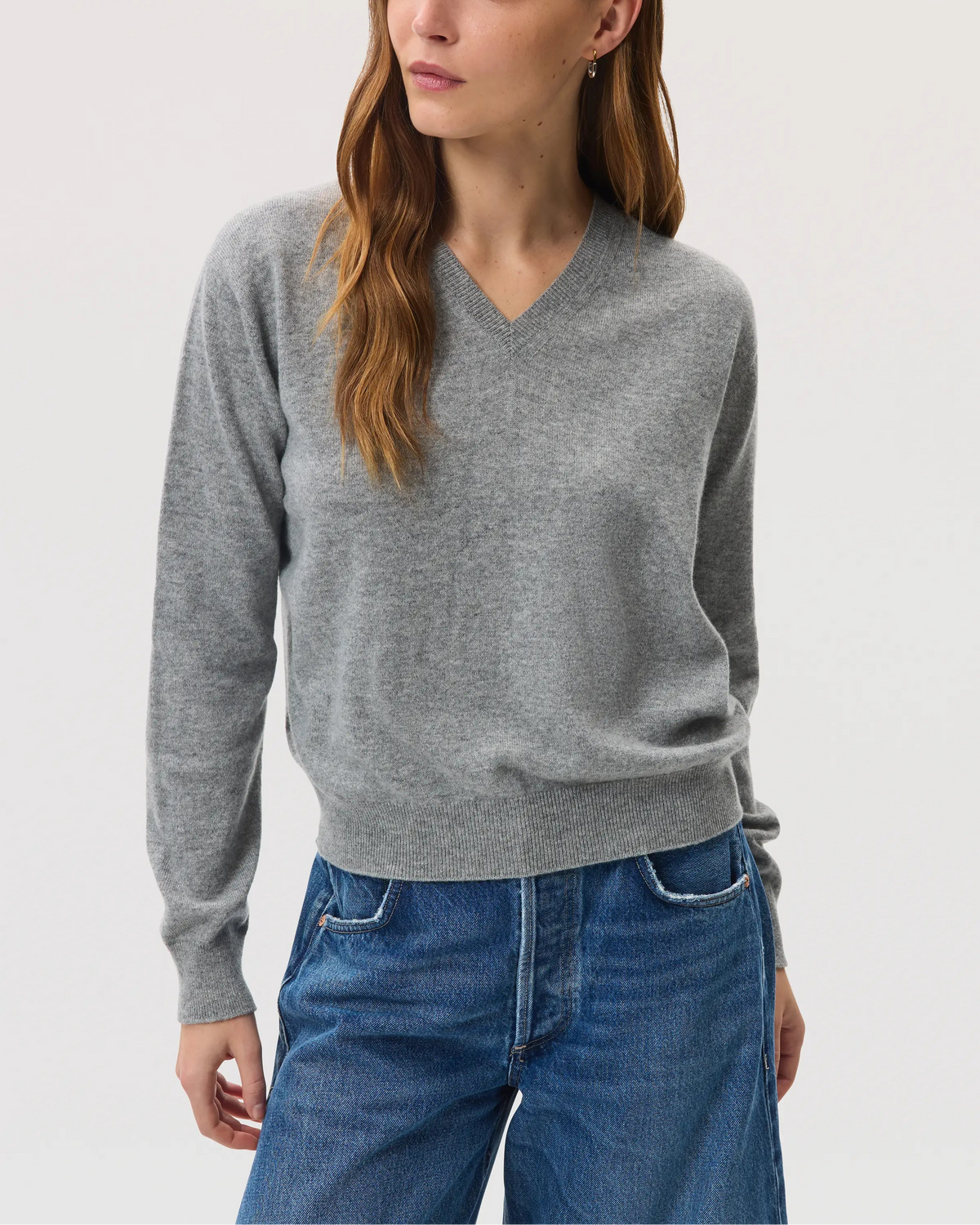 Model wears Johnstons of Elgin SS25 Women's Knitwear Light Grey Classic Cashmere V Neck Sweater with blue barrel leg jeans KAI05143HA0308