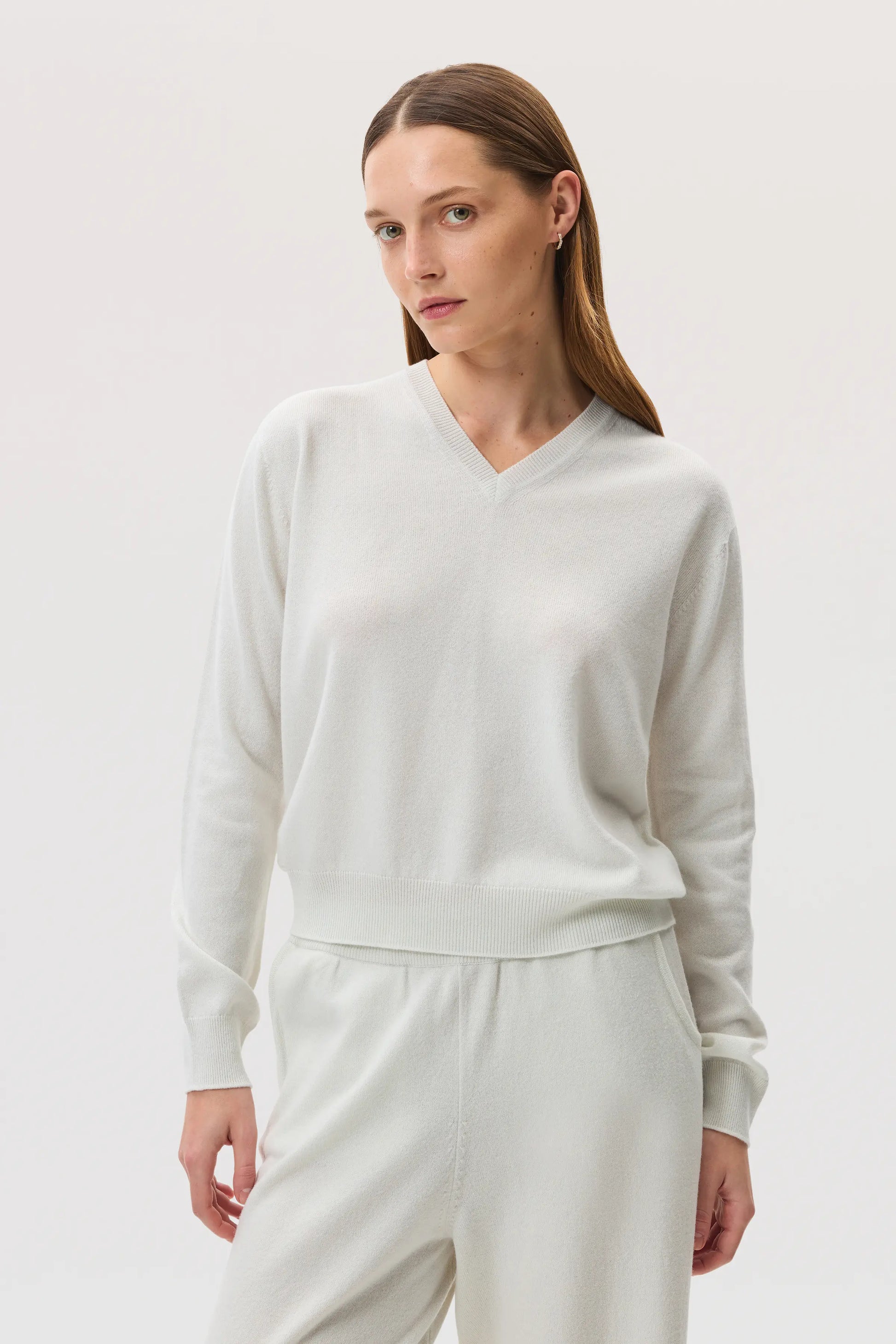 Model wearing Johnstons of Elgin SS25 Women's Knitwear White Classic Cashmere V Neck on a white background  KAI05143HA0346