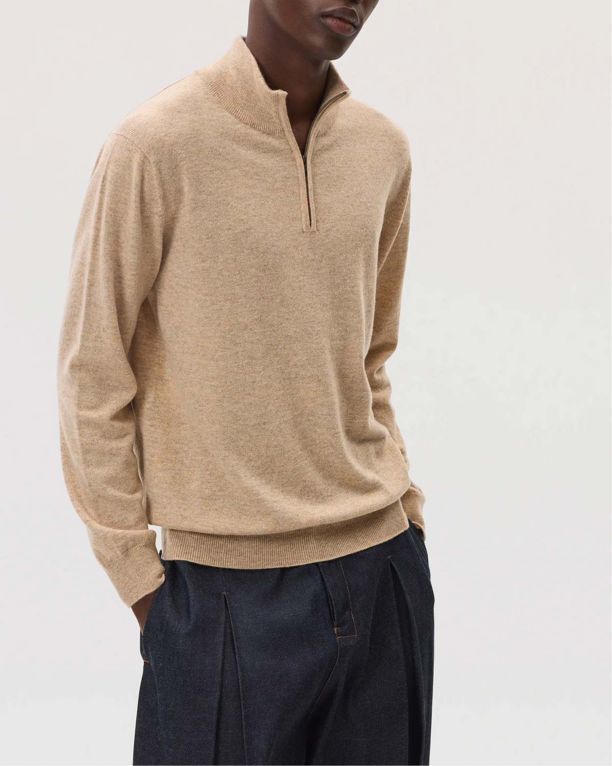 Model wearing Johnstons of Elgin SS25 Men's Knitwear Oatmeal Classic Cashmere Zip Neck with navy trousers KAI05151HB0210