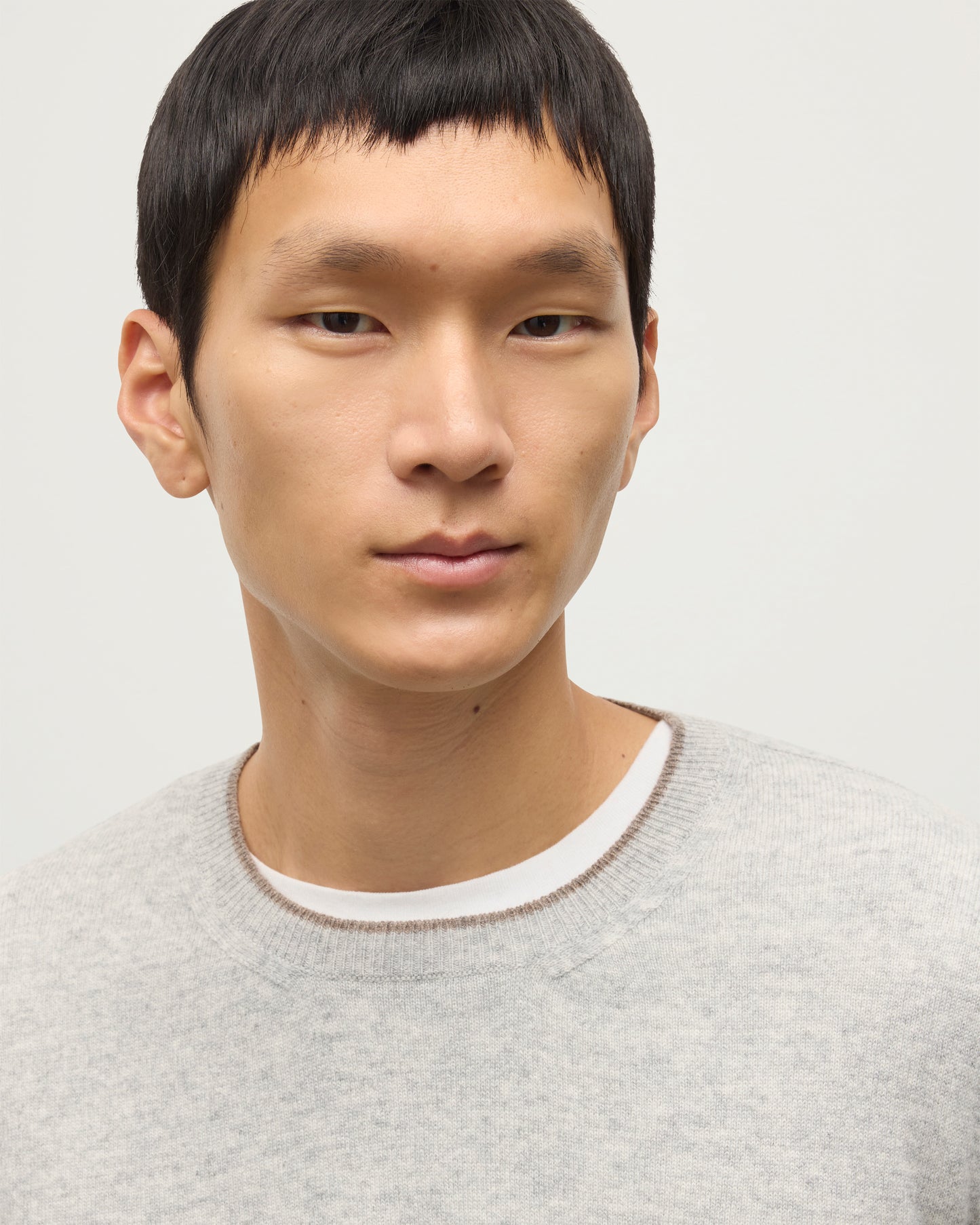 MODEL WEARING JOHNSTONS OF ELGIN MENS SHADED CREW SWEATER LIGHT GREY 100% CASHMERE OVER A WHITE T-SHIRT WITH GREY TROUSERS KAI05232Q25946