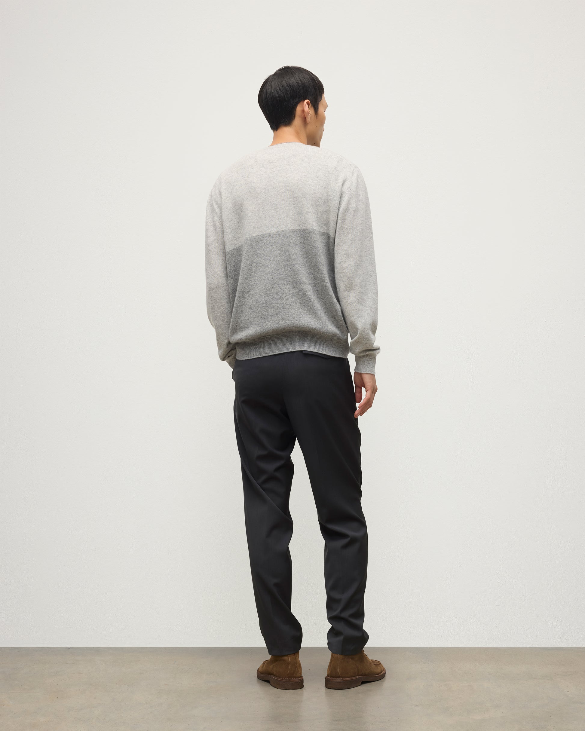 MODEL WEARING JOHNSTONS OF ELGIN MENS SHADED CREW SWEATER LIGHT GREY 100% CASHMERE OVER A WHITE T-SHIRT WITH GREY TROUSERS KAI05232Q25946