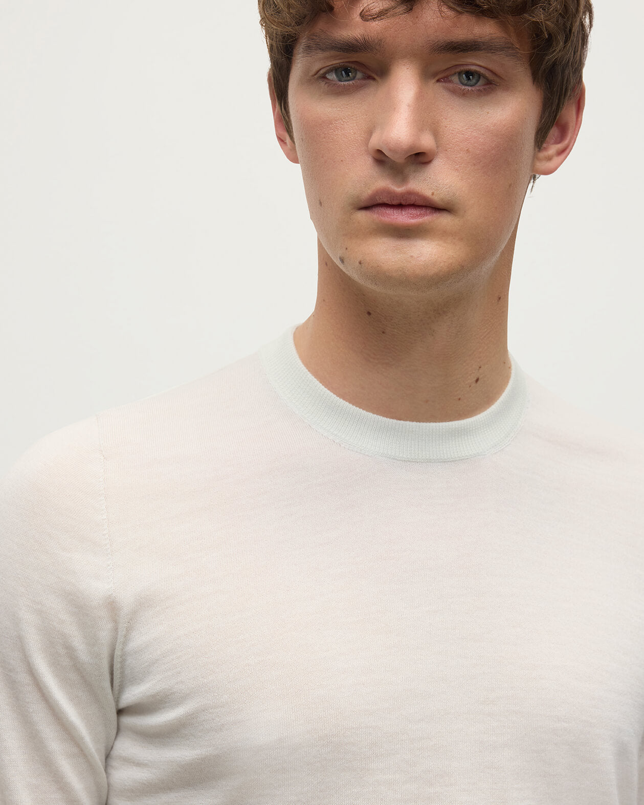 model wearing Johnstons of Elgin AW25 Men's Knitwear White Superfine Cashmere V Neck Jumper  against a white backdrop  KAI05242HA0327