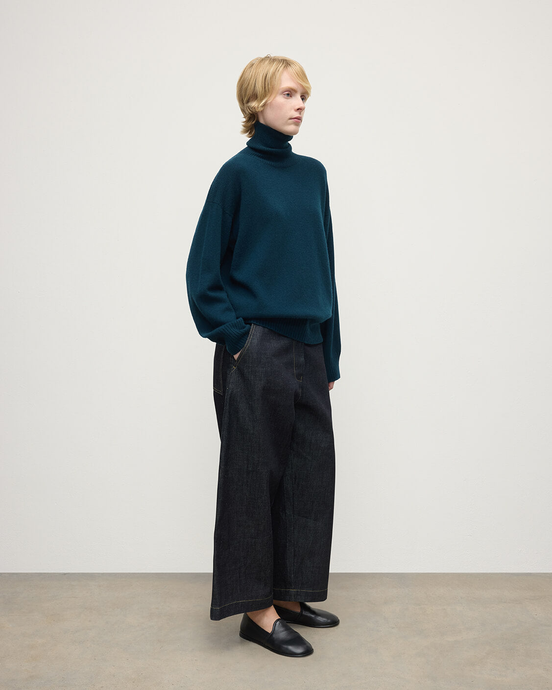 Model wears Johnstons of Elgin AW25 Women's Knitwear Bottle Green Gauzy Cashmere Green Roll Neck Jumper Side View KAI05324SC7341