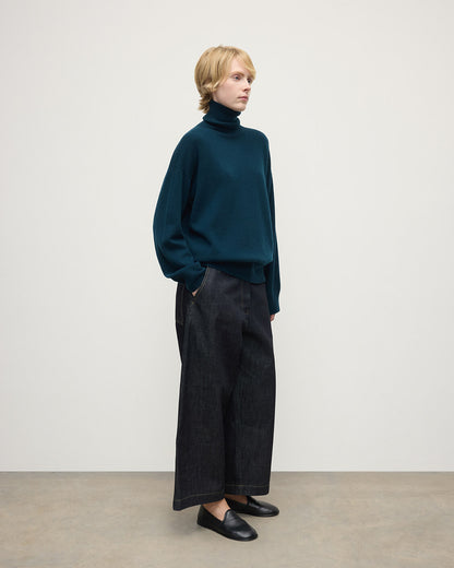 Model wears Johnstons of Elgin AW25 Women's Knitwear Bottle Green Gauzy Cashmere Green Roll Neck Jumper Side View KAI05324SC7341