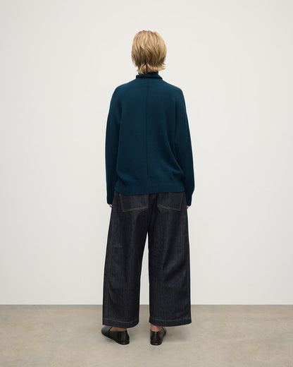 Model wears Johnstons of Elgin AW25 Women's Knitwear Bottle Green Gauzy Cashmere Green Roll Neck Jumper Back View KAI05324SC7341