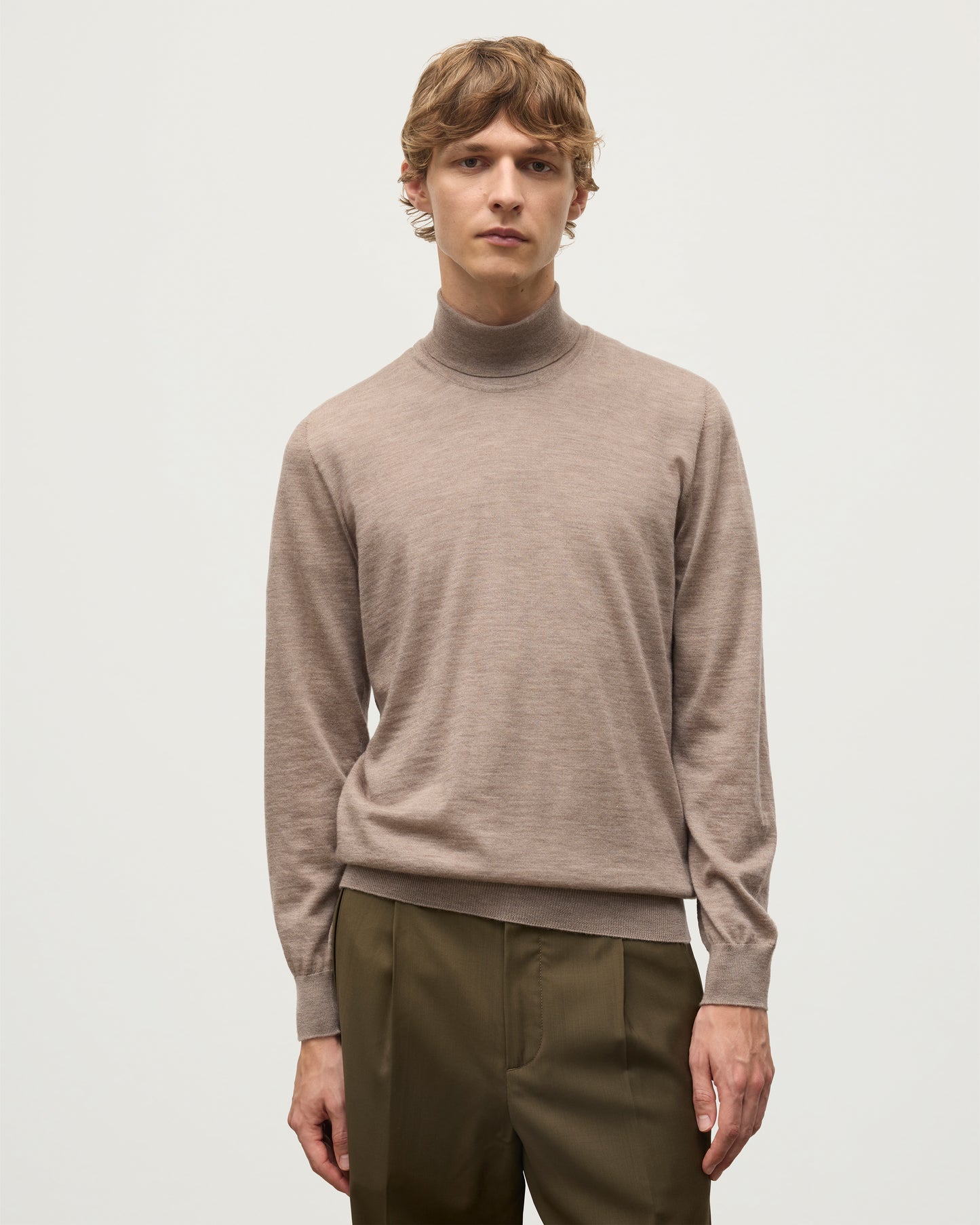 MODEL WEARING JOHNSTONS OF ELGIN MENS SUPERFINE FIN ROLL COLLAR GREY 100% SUPERFINE CASHMERE WITH OLIVE TROUSERS KAI05333HB0273