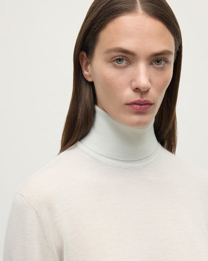 Model wearing Johnstons of Elgin AW25 Women's Knitwear Zinc White Superfine Cashmere White Roll Neck Jumper Close Up  KAI05607HA0327