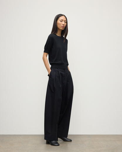 MODEL WEARS JOHNSTONS OF ELGIN WOMENS HONOR SHORT SLEEVE CREW BLACK 100% SUPERFINE CASHMERE WITH BLACK TROUSERS AND BOOTS KAI05712SA7146