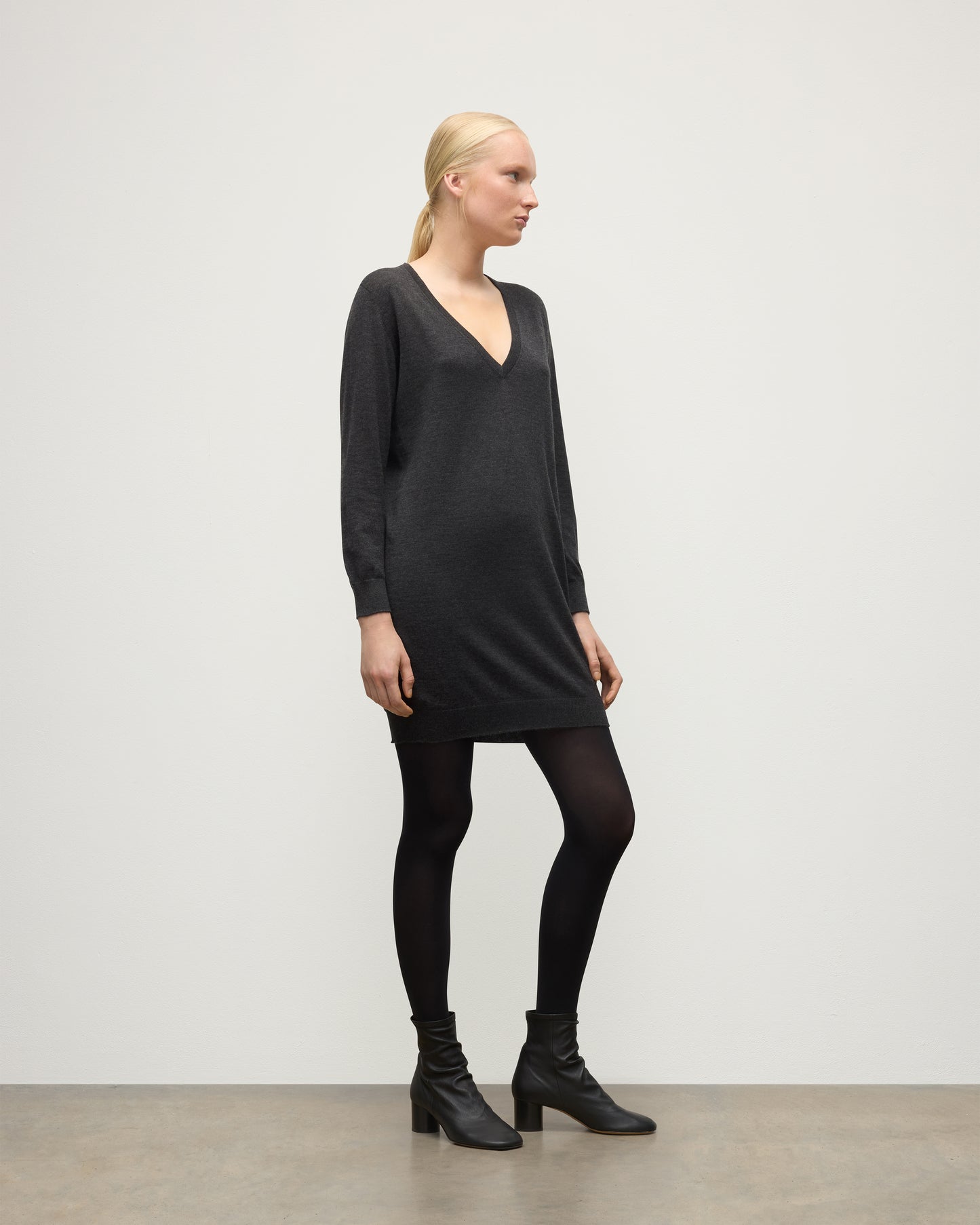 MODEL WEARING JOHNSTONS OF ELGIN WOMENS ELISE VEE SWEATER GREY 100% SUPERFINE CASHMERE WITH BLACK TIGHTS AND BOOTS KAI05715HA7218