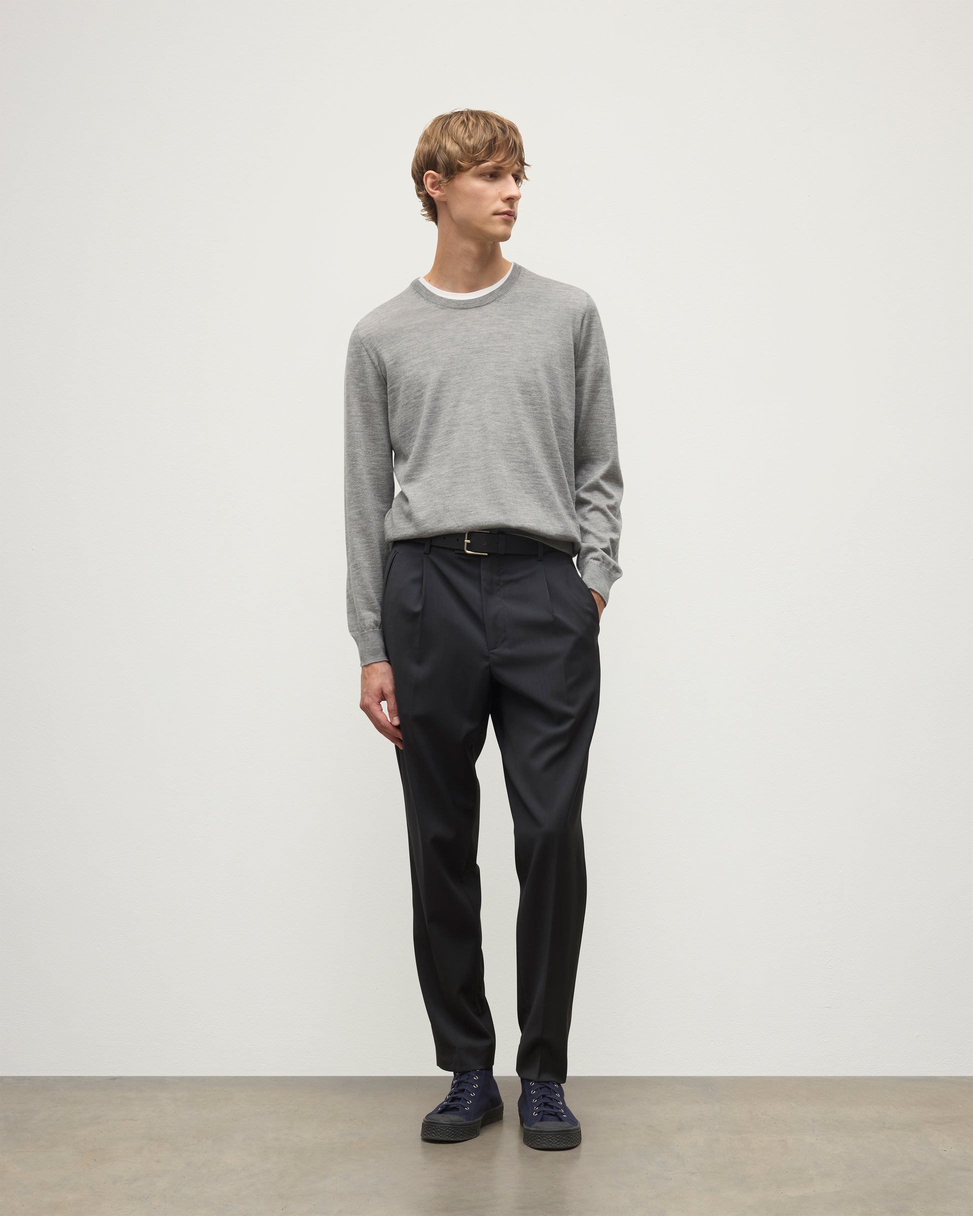 MODEL WEARS JOHNSTONS OF ELGIN MENS FIN SUPERFINE CREW GREY 100% SUPERFINE CASHMERE  OVER A WHITE T-SHIRT WITH GREY TROUSERS KAI05717HA4253