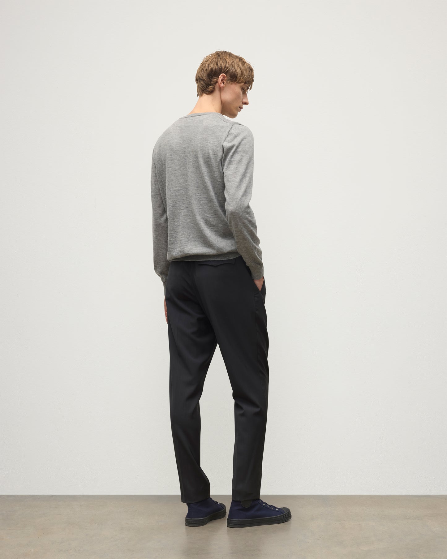 MODEL WEARS JOHNSTONS OF ELGIN MENS FIN SUPERFINE CREW GREY 100% SUPERFINE CASHMERE  OVER A WHITE T-SHIRT WITH GREY TROUSERS KAI05717HA4253