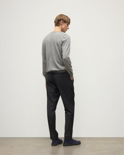 MODEL WEARS JOHNSTONS OF ELGIN MENS FIN SUPERFINE CREW GREY 100% SUPERFINE CASHMERE  OVER A WHITE T-SHIRT WITH GREY TROUSERS KAI05717HA4253