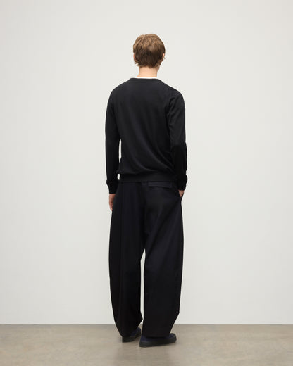 MODEL WEARS JOHNSTONS OF ELGIN MENS FIN SUPERFINE CREW BLACK 100% SUPERFINE CASHMERE OVER A WHITE T-SHIRT WITH BLACK TROUSERS KAI05717SA7146