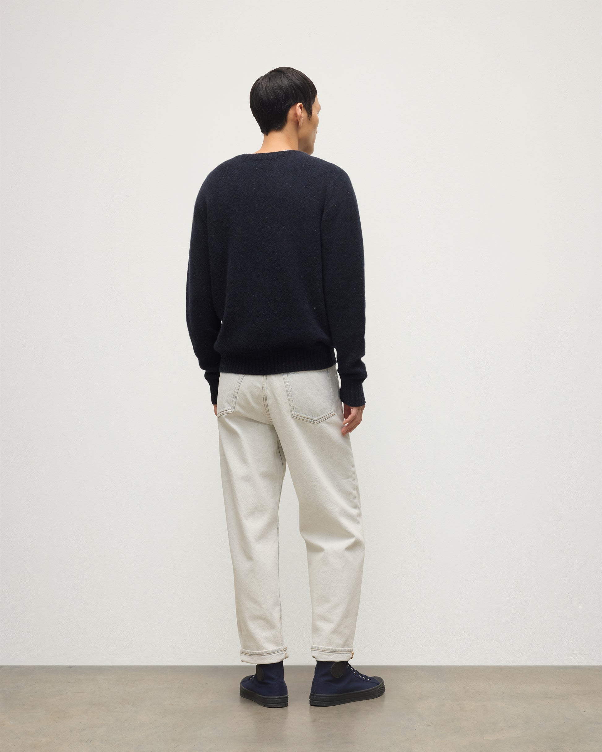 MODEL WEARS JOHNSTONS OF ELGIN  MENS TIREE CREW SWEATER BLUE 100% DONEGAL CASHMERE WITH WHITE JEANS KAI05755HD7348