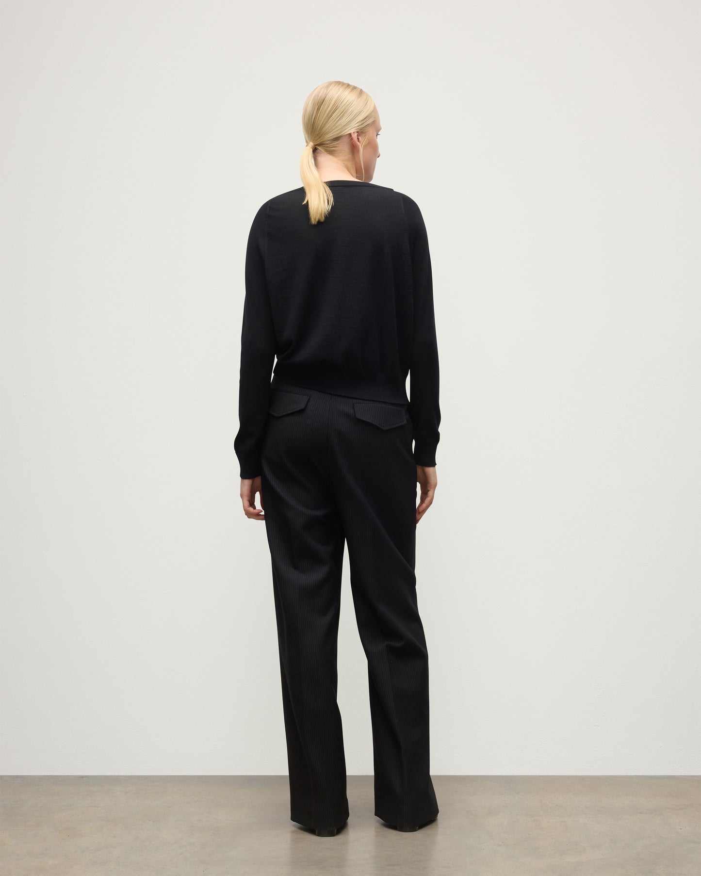 BACK OF JOHNSTONS OF ELGIN WOMENS FINOLA SWEATER BLACK 100% SUPERFINE CASHMERE ON A MODEL WITH BLACK TROUSERS AND BOOTS KAI05789SA7146
