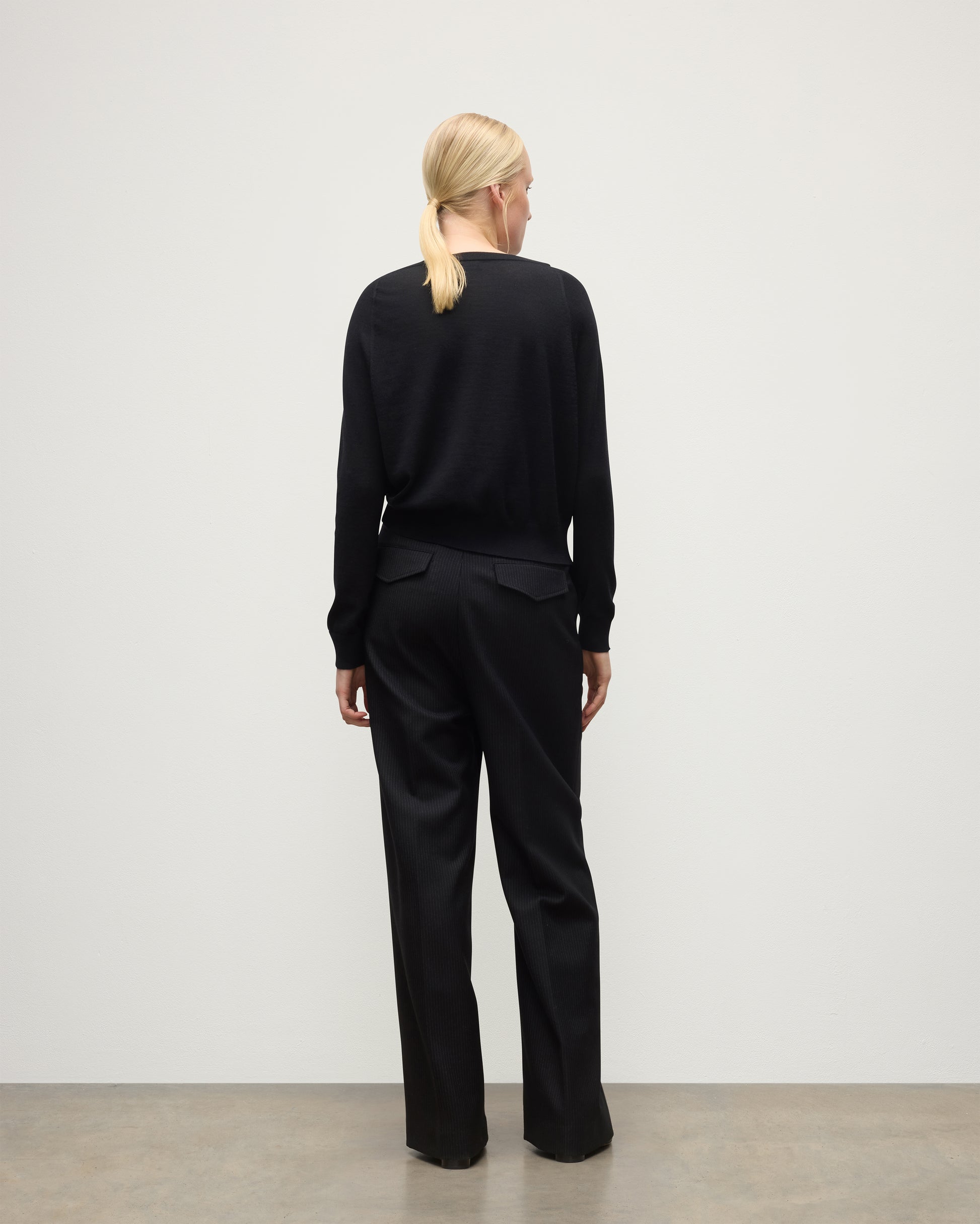 BACK OF JOHNSTONS OF ELGIN WOMENS FINOLA SWEATER BLACK 100% SUPERFINE CASHMERE ON A MODEL WITH BLACK TROUSERS AND BOOTS KAI05789SA7146