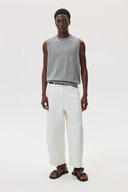Male model wearing Johnstons of Elgin SS25 Unisex Knitwear Light Grey Cashmere Tank and white trousers against a white background  KAP05243HA0308