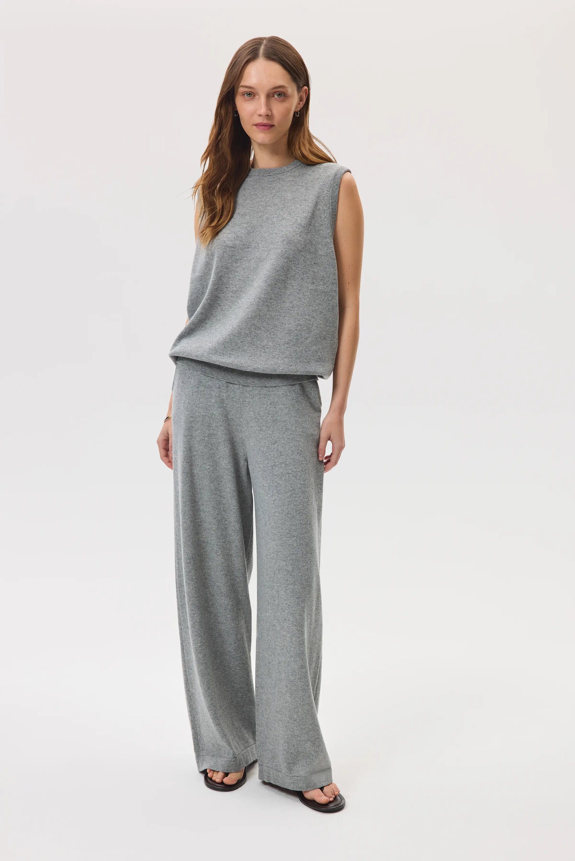 Female model wearing Johnstons of Elgin SS25 Unisex Knitwear Light Grey Cashmere Tank and matching cashmere culottes and sandals against a white background  KAP05243HA0308