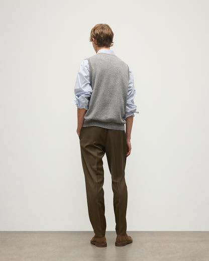 MODEL WEARS JOHNSTONS OF ELGIN MENS LENNOX SLEEVELESS CREW GREY 100% CASHMERE OVER A LIGHT BLUE SHIRT WITH OLIVE GREEN TROUSERS KAP05243HA0400