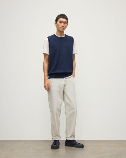 MODEL WEARS JOHNSTONS OF ELGIN MENS LENNOX SLEEVELESS CREW NAVY 100% CASHMERE, OVER A WHITE SHORT SLEEVE T-SHIRT WITH WHITE JEANS KAP05243HD7350