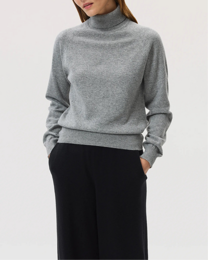 Model wears Johnstons of Elgin SS25 Women's Knitwear Light Grey Classic Cashmere Roll Neck Sweater with black wide leg trousers  KAP05275HA0308