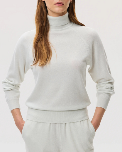 Model wears Johnstons of Elgin SS25 Women's Knitwear White Classic Cashmere Roll Neck Sweater with 
 matching cashmere culottes KAP05275HA0346